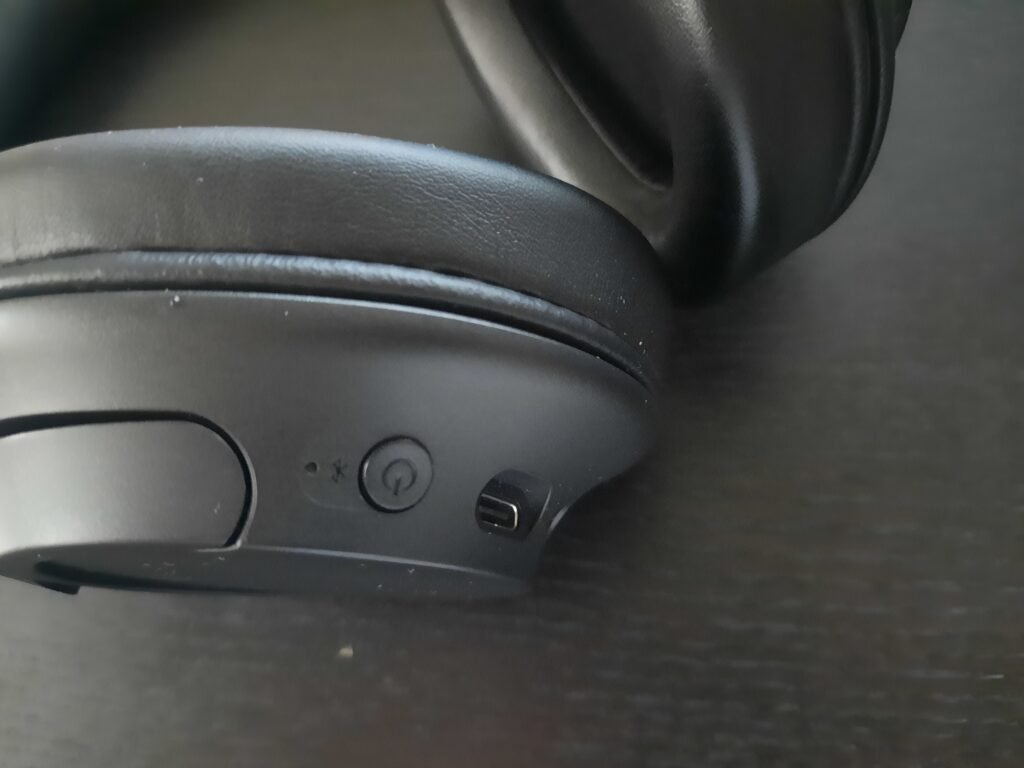 In this image, the power button and c-type slot of the Sony WH-CH720N noise-canceling wireless headphones.